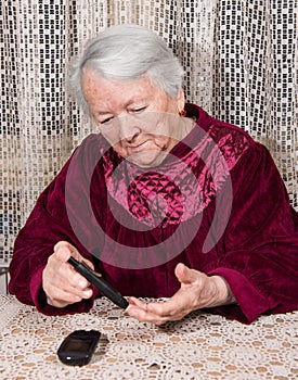 Old woman with glucometer checking blood sugar level