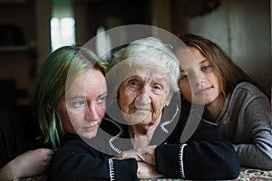 An old woman granny is photographed for portrait with her great-granddaughters. Family.