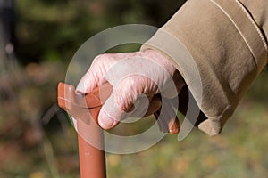 Old woman hand leans on walking stick