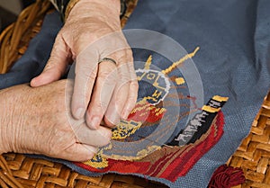 Old woman hand with a needle and a thread