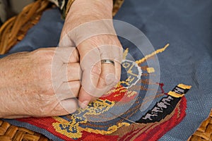 Old woman hand with a needle and a thread