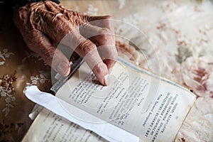 Old woman hand on the open prayer book