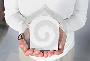 Old woman hands holding house model and key