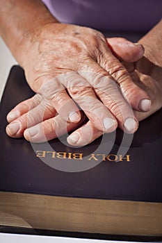 Old woman hands on Holy Bible