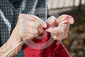 Old woman hands knitting a red sweater