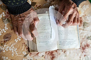 Old woman hands on the open prayer book