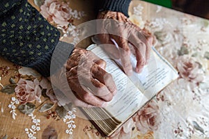 Old woman hands on the open prayer book