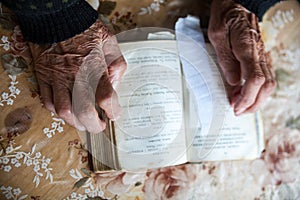 Old woman hands on the open prayer book