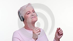 Old Woman in Headphones Listening to Music and Dancing on White Background