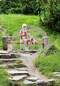 Old woman and her dog sitting on a bench