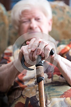 Old woman with her hands on a cane