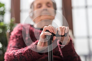 Old woman with her hands on a cane