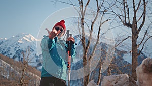 old woman hiking in the winter mountains. Senior female uses sticks for Nordic walking. Snowy peaks