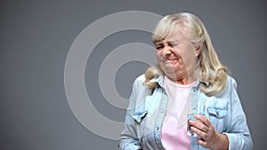 Old woman holding beverage and wrinkling with disgust, water pollution concept