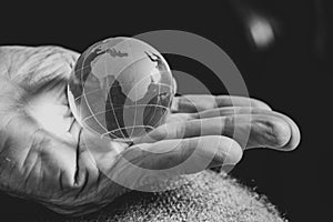 old woman holding a glass globe in her hands, black and white photo, the world is in hands