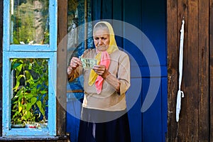 The old woman is holding money in her hands. An elderly woman with dollars in her hands