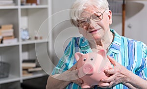 Old woman holding a piggy bank