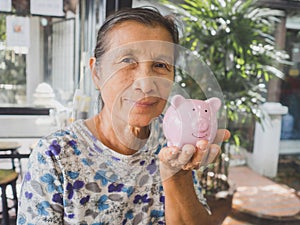 Old woman holding Pink piggy bank. Saving money for future plan and retirement fund concept