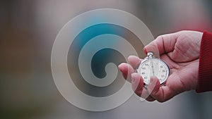 An old woman is holding a round pocket watch.