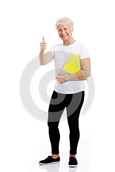 An old woman holding workbook and showing OK.