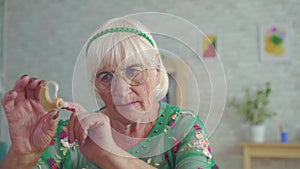 Old woman holds and consider a hearing aid sitting