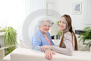 Old woman at home with cheerful young girl spending time together with laptop computer