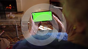 Old woman at home using a mobile phone with green screen. Mockup device