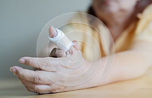 Old woman Injured painful finger with white gauze bandage. Selective focus, close up