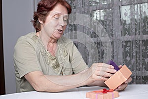 Old woman looking at gift box accepting present