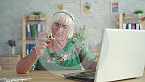 Old woman is looking for information about a hearing aid in a laptop