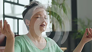 Old woman make yoga exercise at home. Mature woman have meditation. she sits down on the bed mat,close eyes and deep