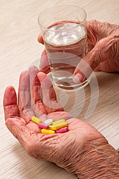 Old woman with pills in the palm of your hand