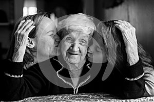 An old woman posing for a portrait with two granddaughters.
