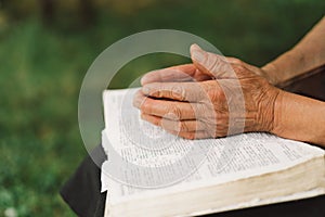 Old woman praying for hope or reading holy bible