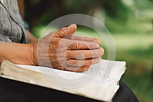 Old woman praying for hope or reading holy bible