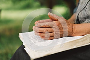 Old woman praying for hope or reading holy bible