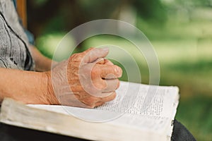 Old woman praying for hope or reading holy bible