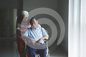 Old woman pushes her husband in a wheelchair