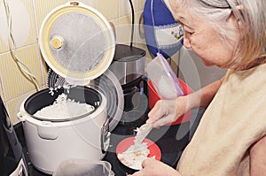Old woman puting white rice on a bowl