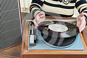 Old woman puts a vinyl record