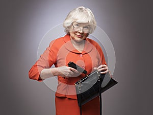 Old woman putting gun in handbag