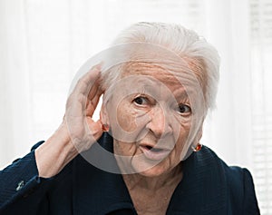 Old woman putting hand to her ear. Bad hearing