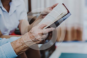 Old woman reading bible together with young woman in home