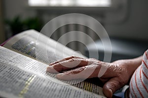 An old woman reads the Bible, hands close up.