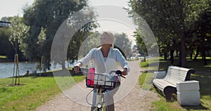 Old woman riding bicycle in summer park