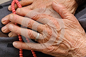 Old woman with ring on her finger worships her hand with rosary photo