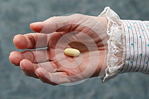 Old woman's hand holding pill