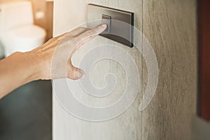 old woman`s hand turned on switch to open light in toilet