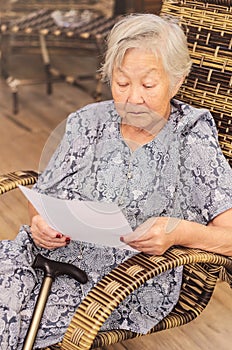 Old woman seated reading carefully a document or terms of a insurance. Old obaasan (grandma), japanese descendant.