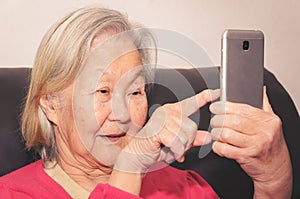Old woman holding a smartphone and touching the screen photo